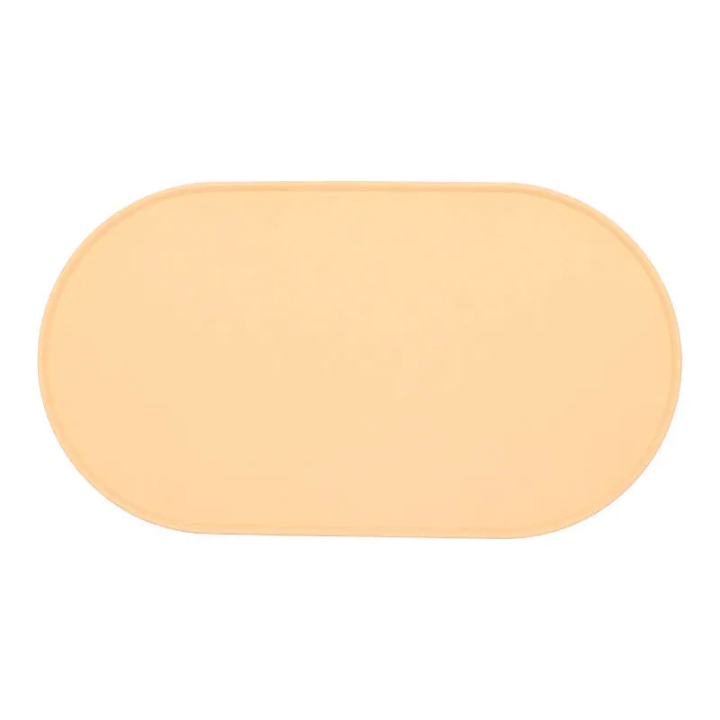 Silicone cat feeding placemat in beige colour, shown under food and water bowls on a kitchen floor.