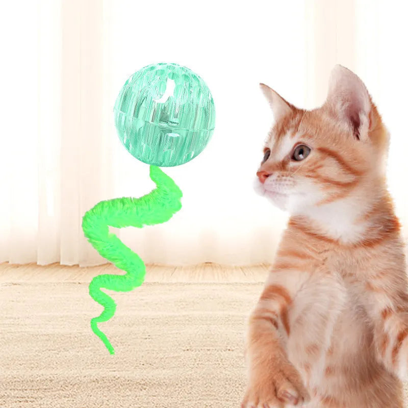 Green bouncy ball cat toy with plush tail on wooden floor
