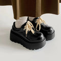 Women's matte black lace-up heeled shoes with thick rubber sole and block heel on a plain background