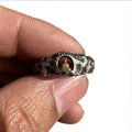 Close-up of a hand-forged copper Grotto Buddha ring with a rough rock texture on a size 8 finger.