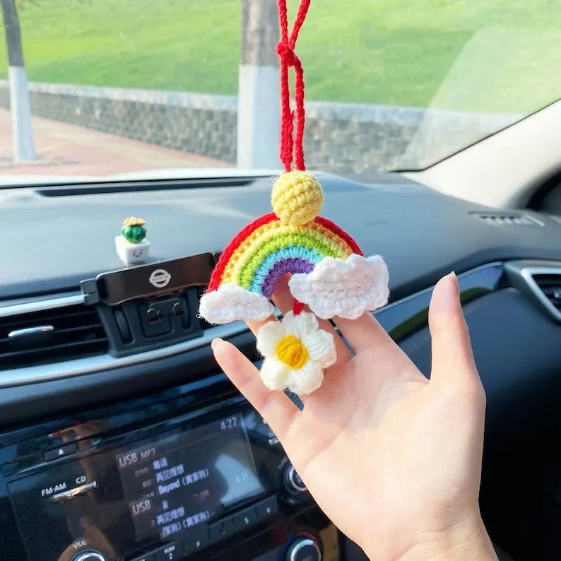 Handmade crocheted avocado-shaped car pendant with a rainbow flower on a green background.
