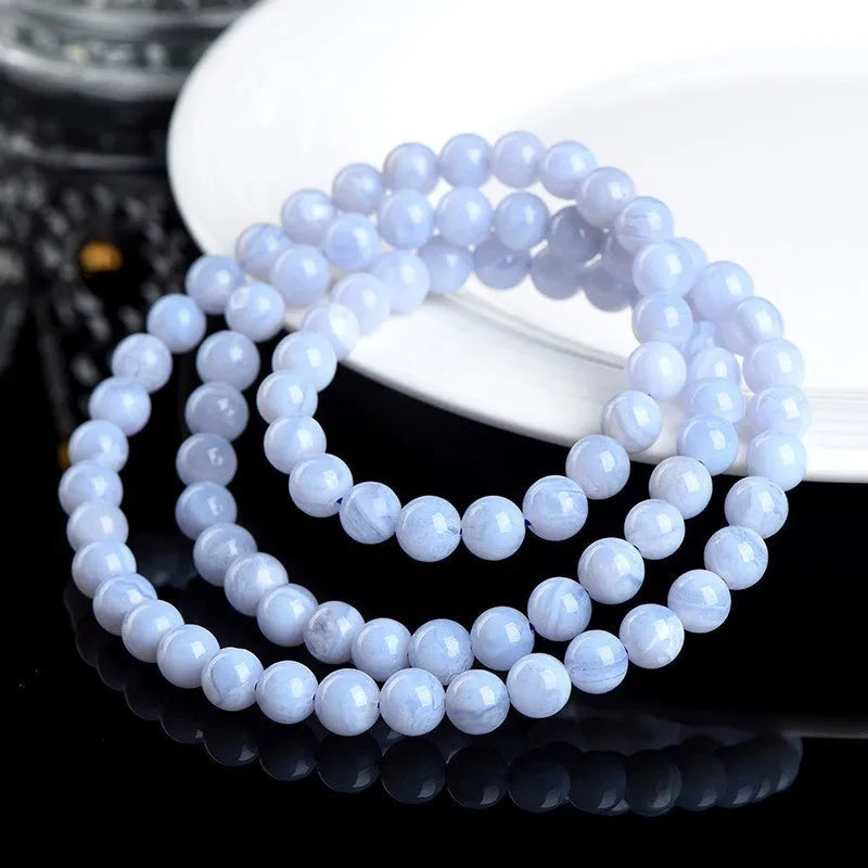 Blue agate bracelet with scattered multi-circle stripes and Ruyi design on wrist.