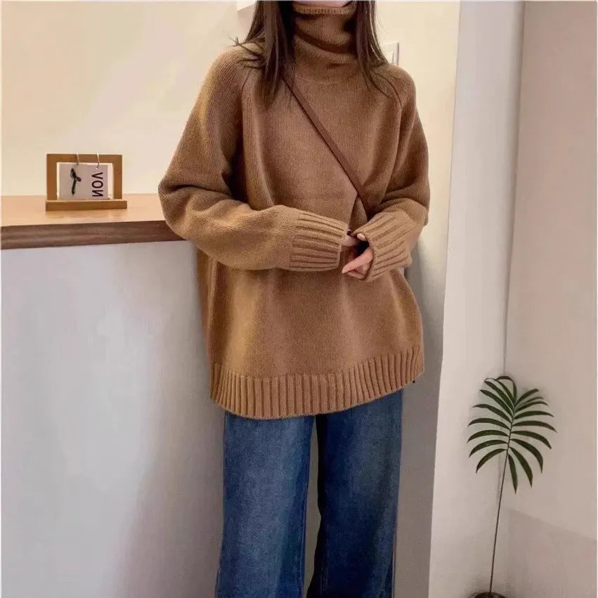 Women's loose grey turtleneck sweater with thick curling pile collar, worn in a casual setting.