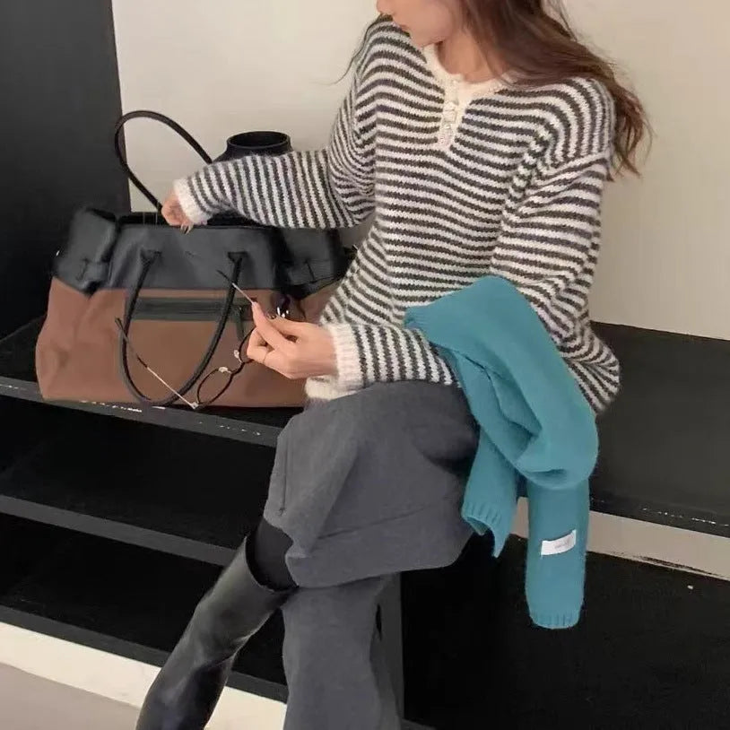 Woman wearing a loose red and blue striped cashmere pullover sweater with long sleeves.