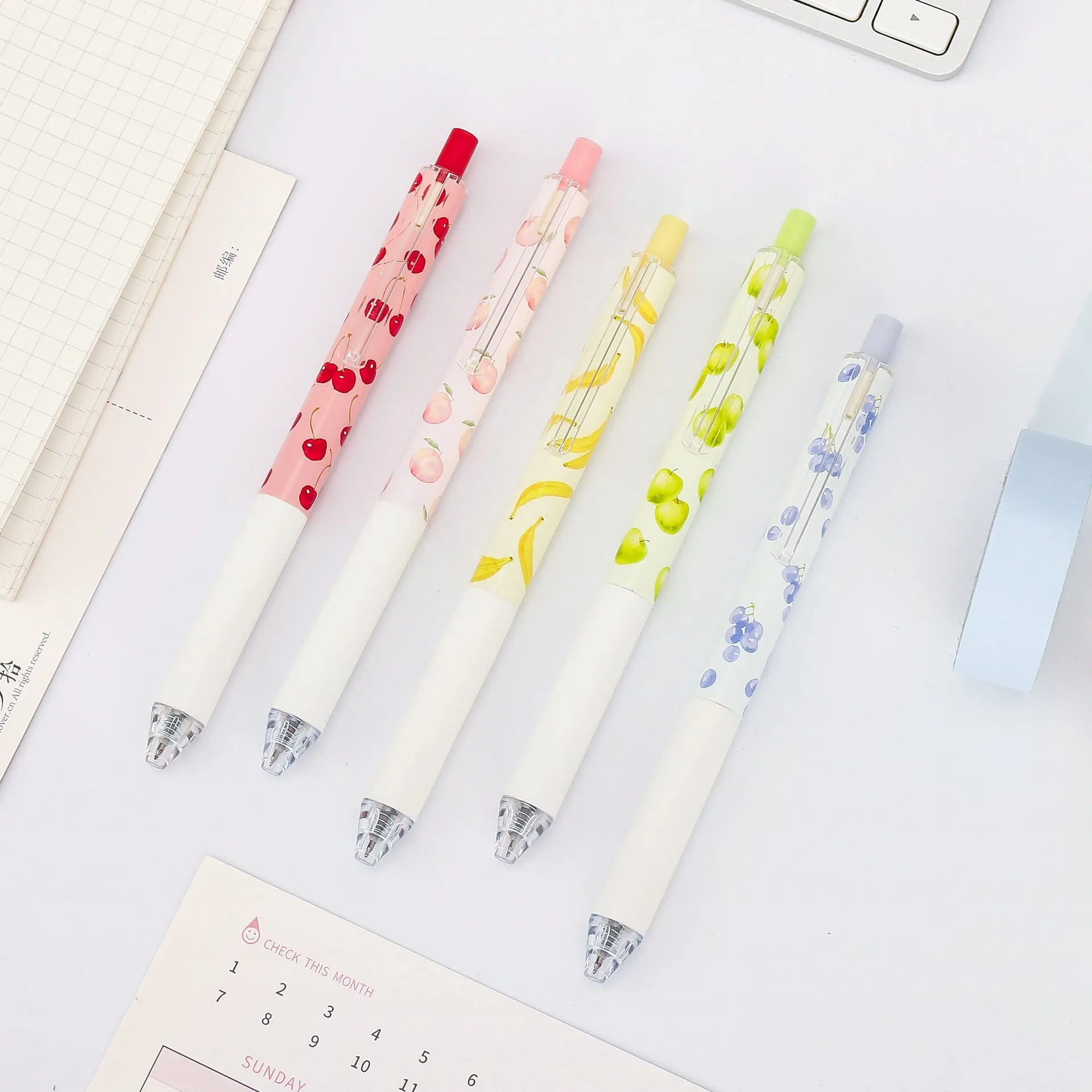 Three fruit scented press-action pens with 0.5mm quick-drying black refills on white background
