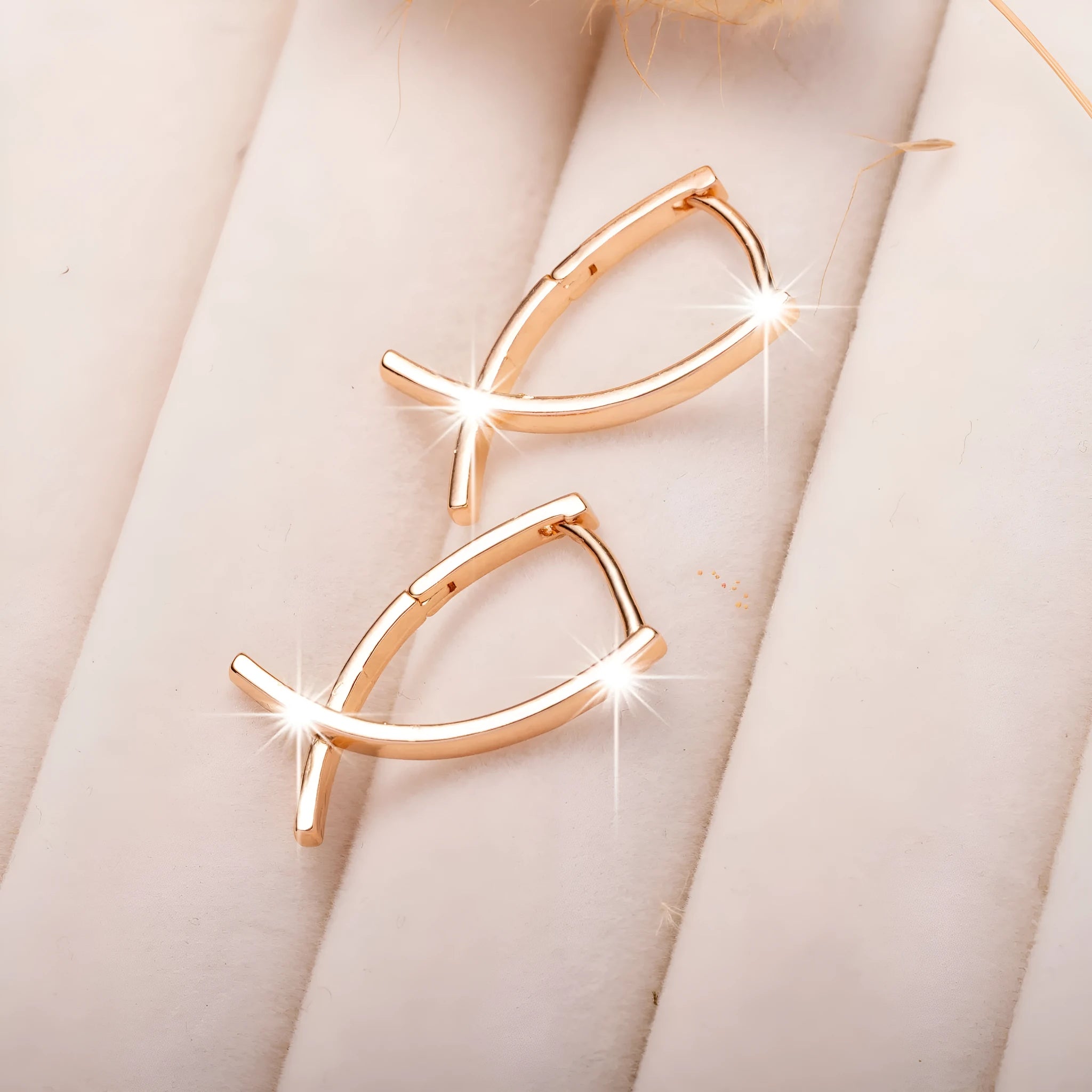A pair of rose gold-coloured copper earrings in a detailed cross shape.