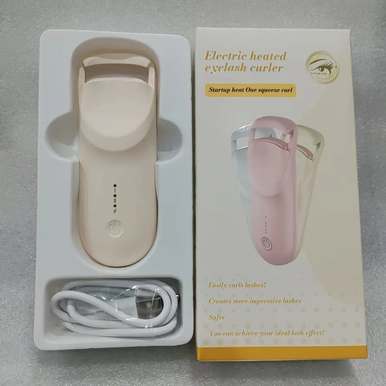 USB electric eyelash curler in cream white, pink, or apricot with charging cable.