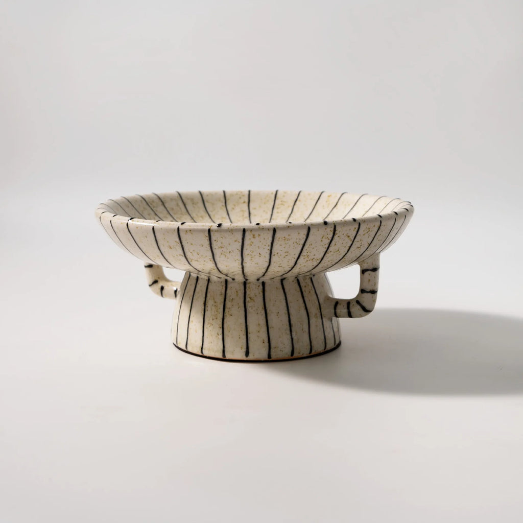 Black and white striped plastic resin fruit plate on a wooden surface.