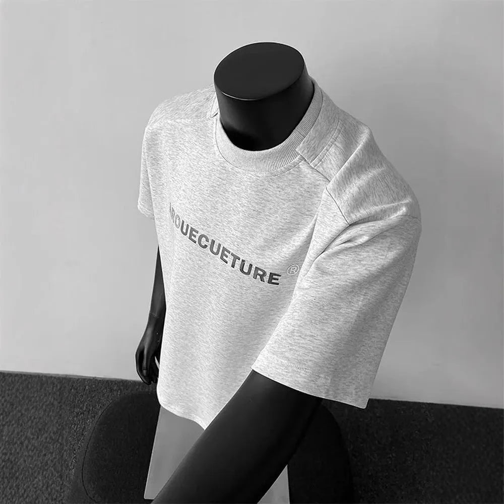 Man wearing a loose grey short sleeve cotton shirt with a letter print design.