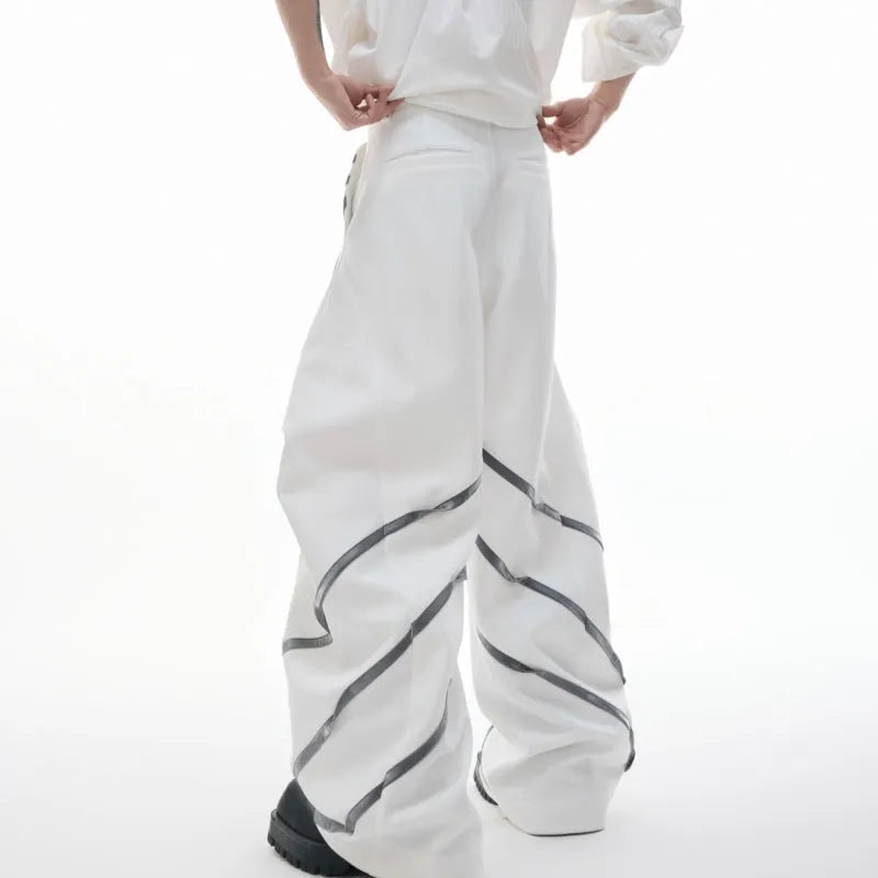 Men's black trousers with white pleated detail and silver metal striped rivets, showing the three-dimensional cut.