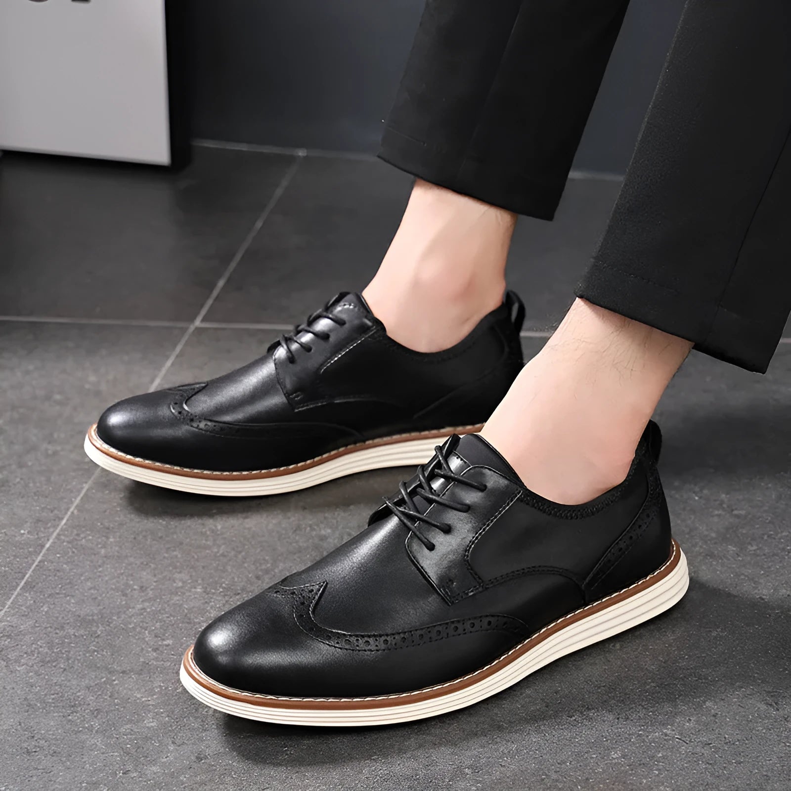 Men's black and brown slip-on casual shoes with round toe and carved detail on the upper.