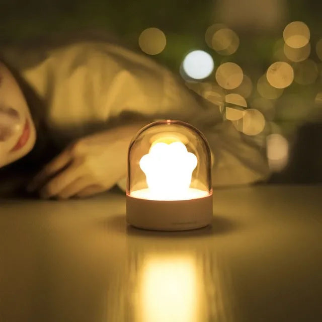 Grey cat paw shaped USB rechargeable night light with music box on a desk.