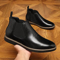 Formal black pointed-toe leather boots with a square heel and rubber sole on a plain background.