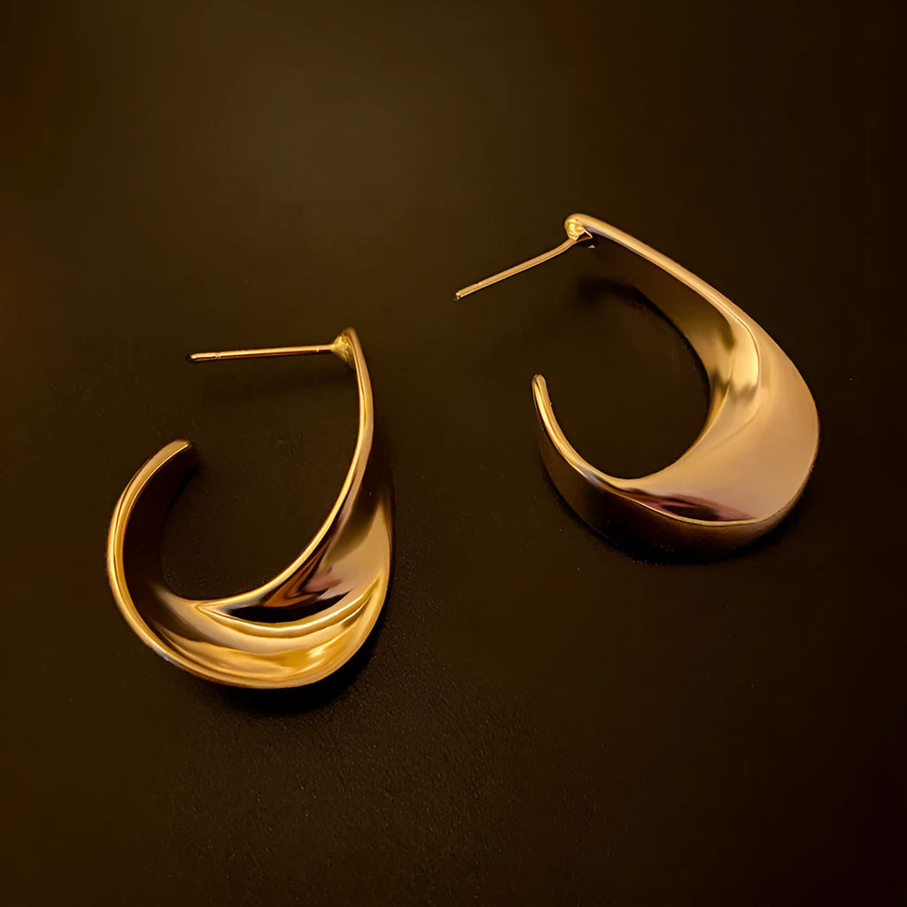 A pair of geometric round earrings with a twisted metal design in a gold electroplated finish.