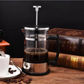 Small glass French press coffee maker with stainless steel plunger, shown with dimensions 10cm by 8cm by 17cm.