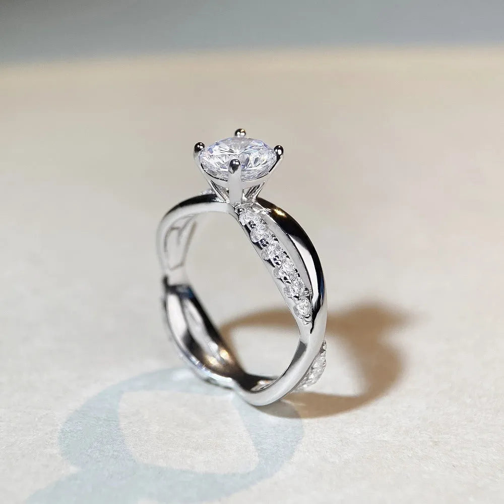 Silver ring with a 1 karat moissanite stone in a four-claw setting and a geometric twisted arm band.