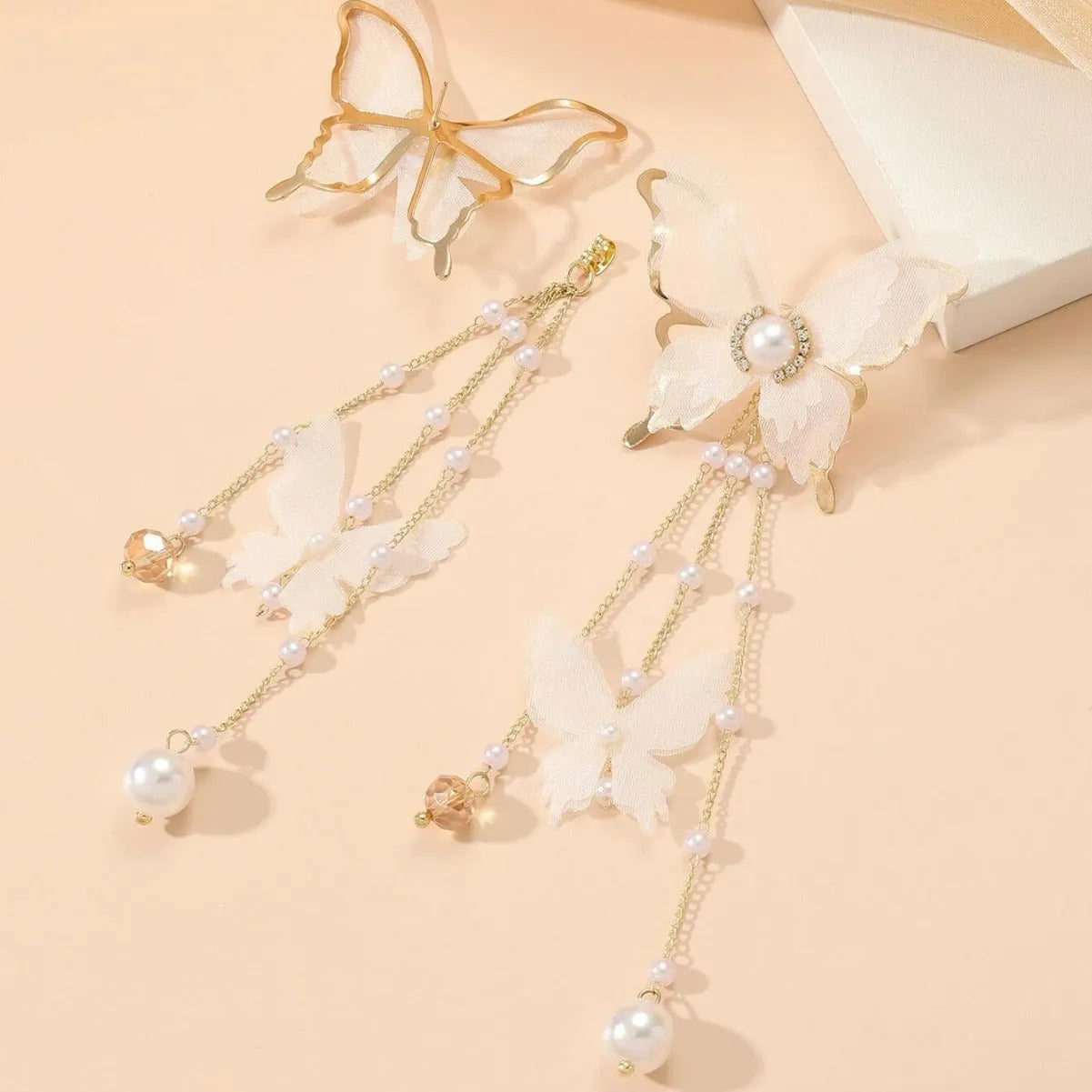White butterfly earrings with lace design, pearl accents, rhinestones, and tassel on electroplated copper alloy
