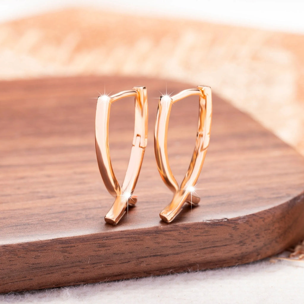 A pair of rose gold-coloured copper earrings in a detailed cross shape.