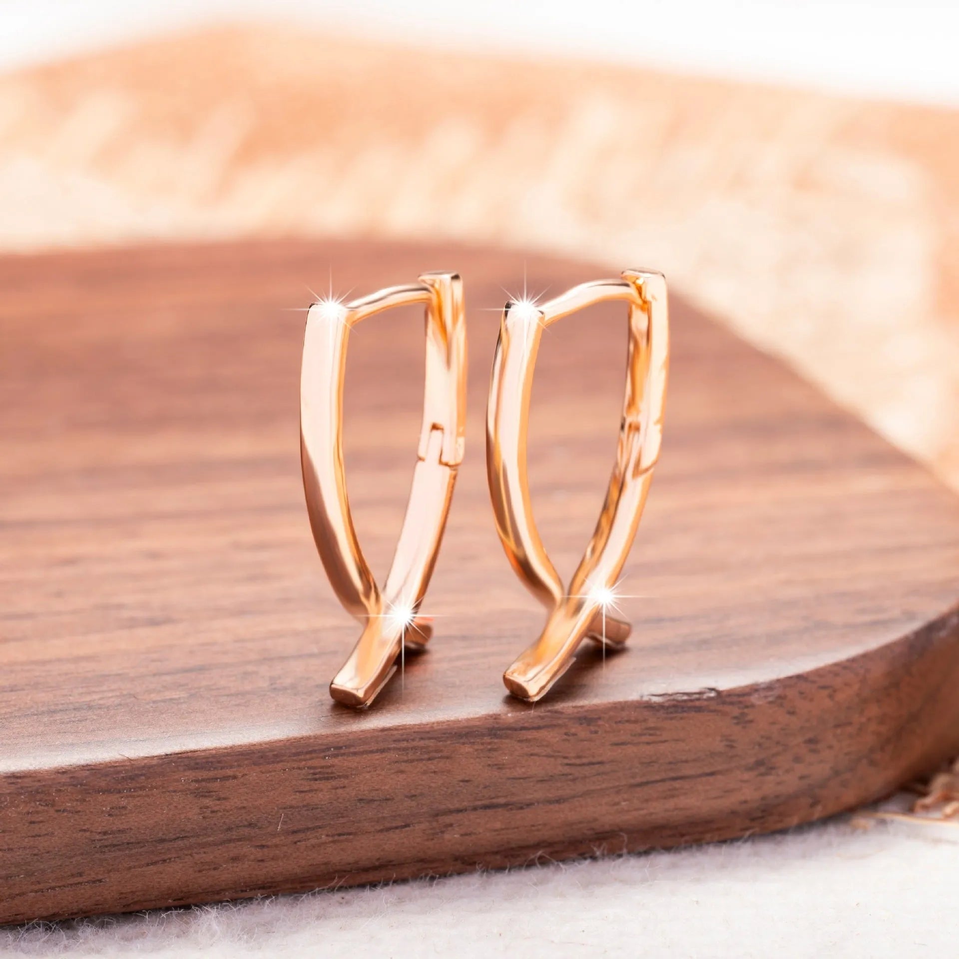 A pair of rose gold-coloured copper earrings in a detailed cross shape.