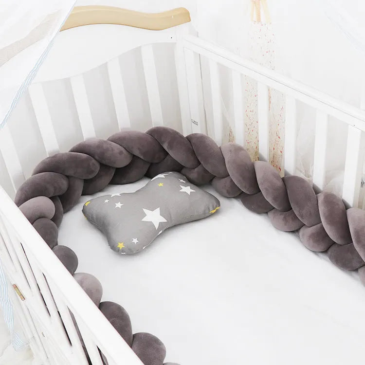 Braided knot pillow cushion bumper for infant crib in spandex velvet, shown in a light colour.