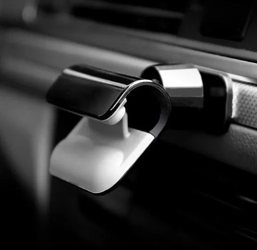 Black 360-degree rotating car phone holder mounted on a car air vent, holding a mobile phone.