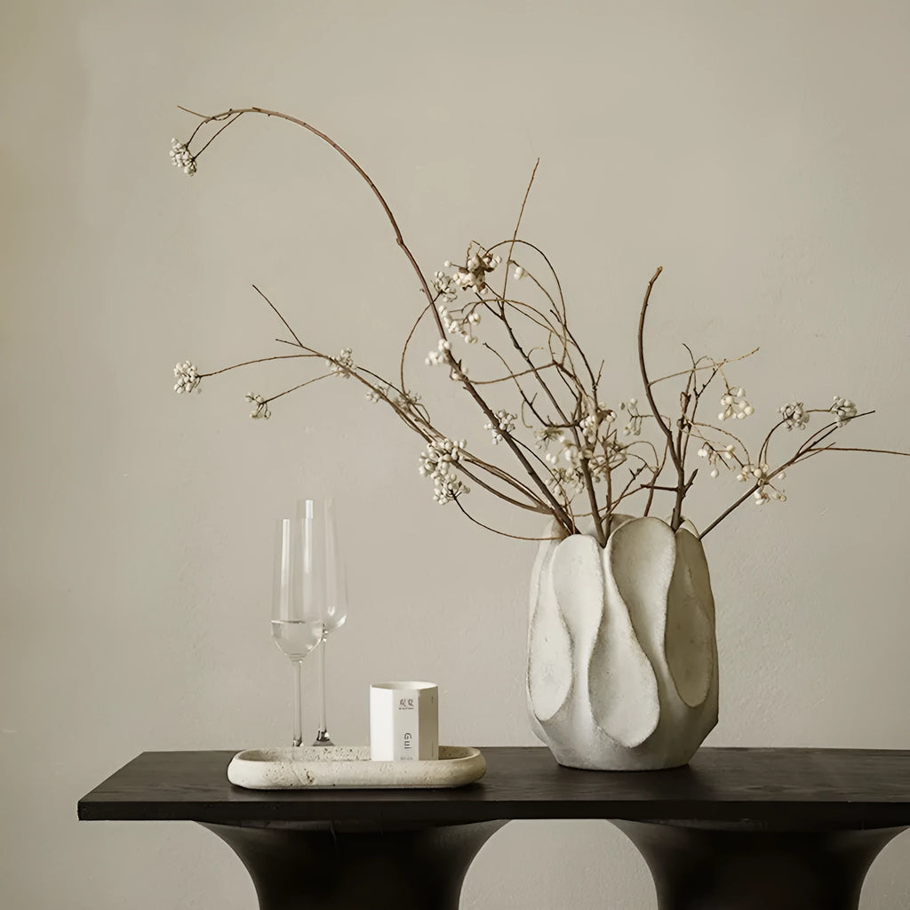 Irregular shaped handcrafted ceramic vase on a wooden surface, showing its artisanal form.