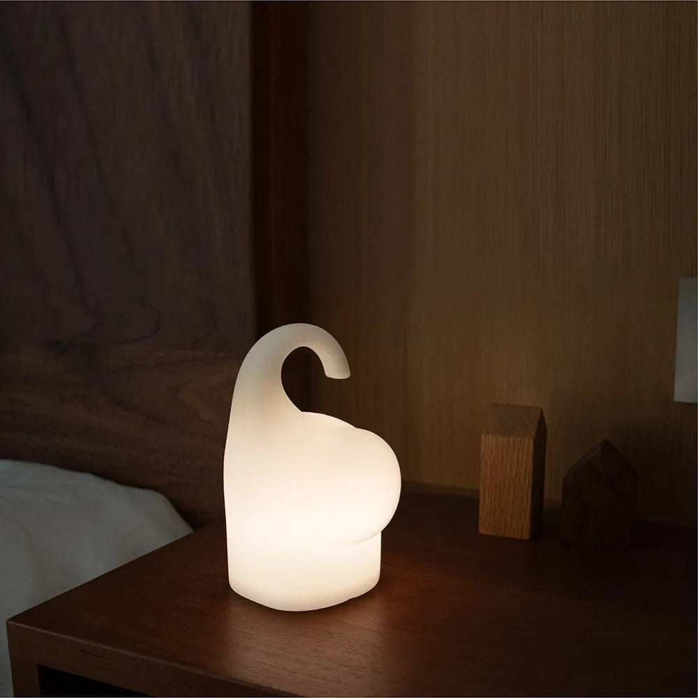 DOMI elephant-shaped silicone night light with warm white glow on a bedside table.
