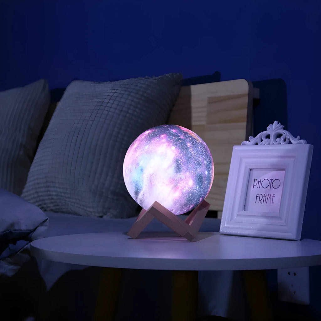 3D printed spherical lunar surface night light glowing with soft yellow and white LED light on a table.
