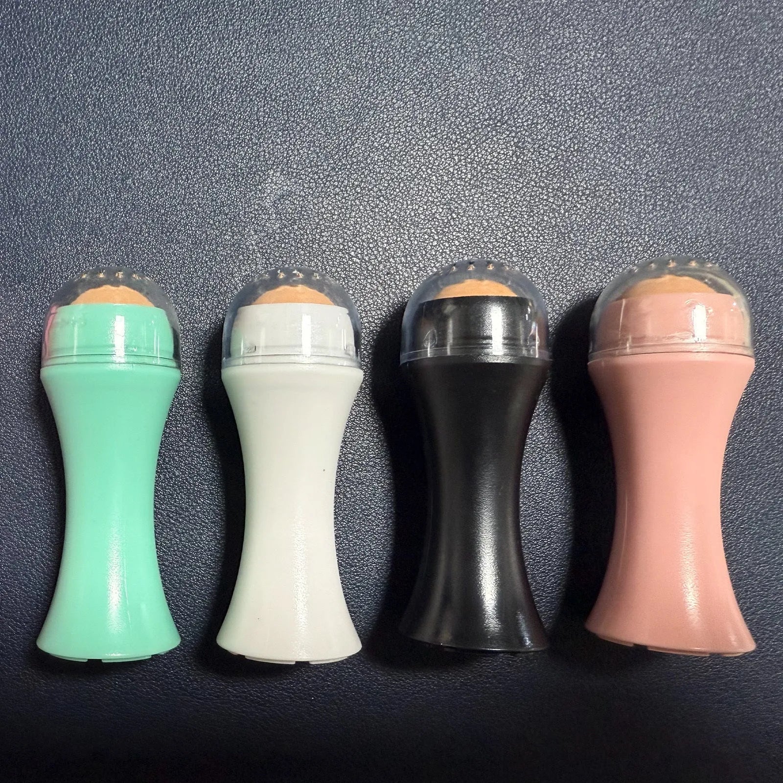 Portable volcanic stone oil absorbing roller in pink on a white background.