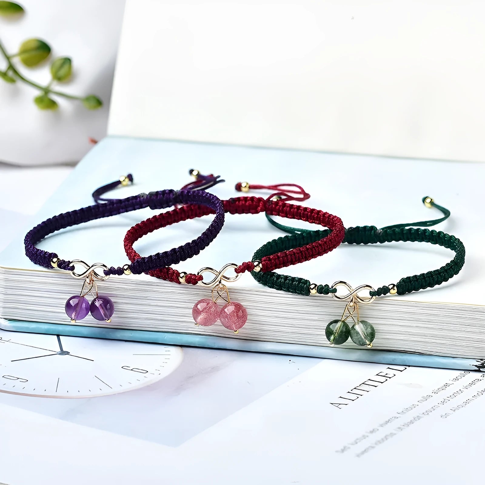 Close-up of a women's natural crystal bracelet with a detailed cherry charm in strawberry quartz colour.