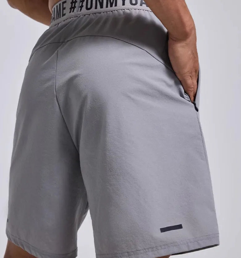 Men's loose black cropped sports shorts with an elastic waistband on a grey background