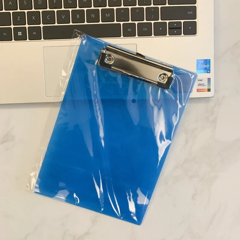 Transparent A4 plate writing board holder with metal clip, shown in blue colour on a desk.