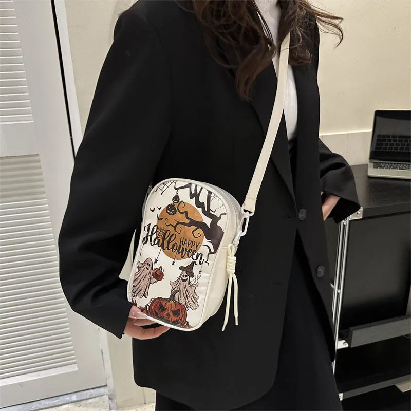 Black mini crossbody bag with Halloween cartoon print of pumpkins, ghosts, and bats.