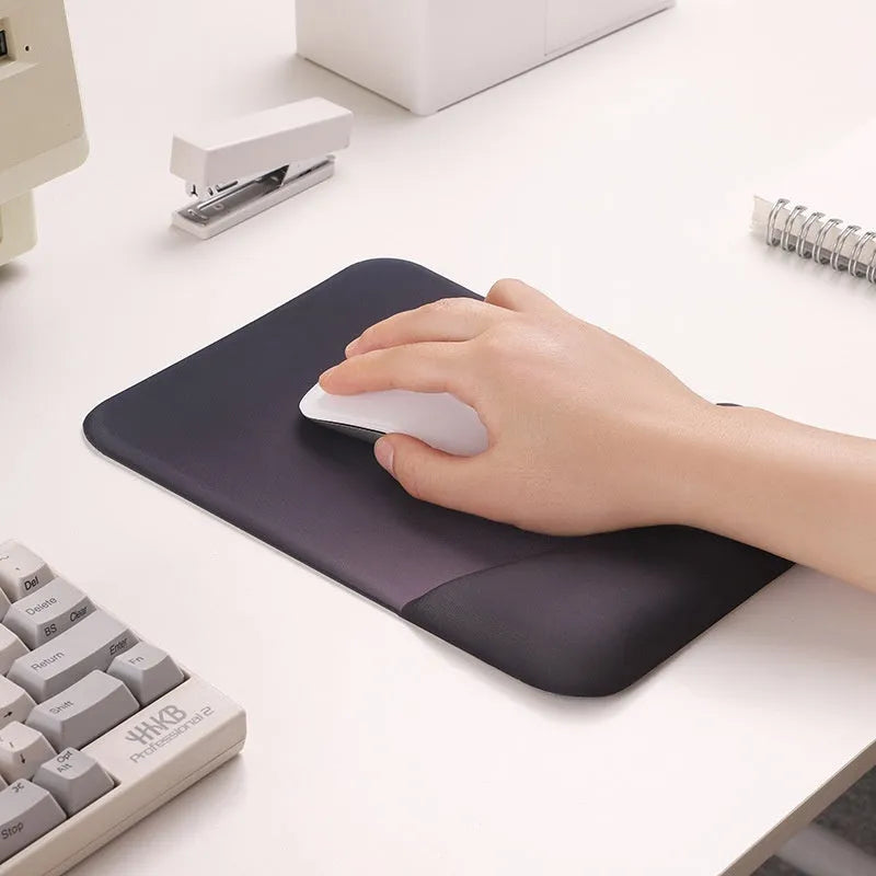 Square black silica gel mouse pad with raised keyboard support area and integrated wrist rest on a wooden desk.