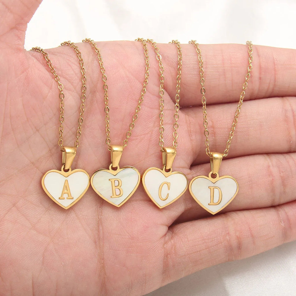 Gold-plated heart necklace with white shell pendant showing initial engraving on stainless steel chain