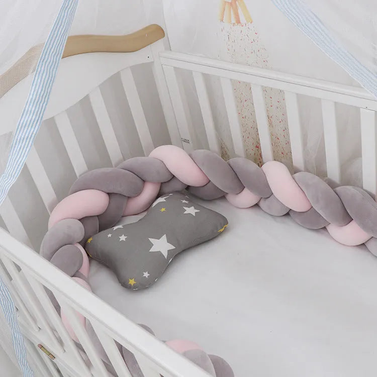 Braided knot pillow cushion bumper for infant crib in spandex velvet, shown in a light colour.