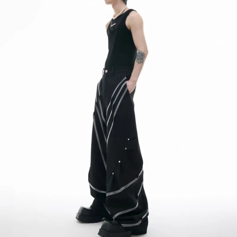 Men's black trousers with white pleated detail and silver metal striped rivets, showing the three-dimensional cut.