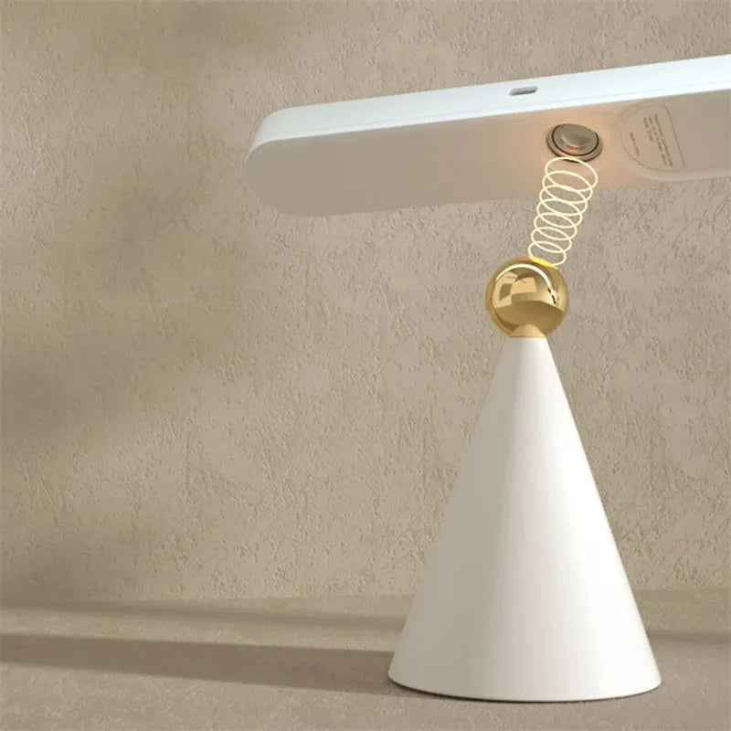 White geometric desk lamp with touch control and magnetic base on a wooden table.