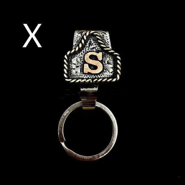 Handmade metal cow tag belt keychain showing one of 26 colour options, each marked with a different alphabet letter.