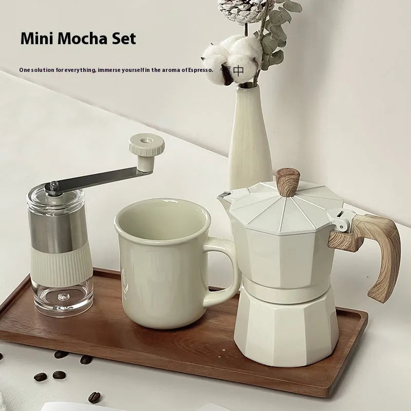 Six-piece manual grinding machine set in beige and black with moka pot, cup, bean jar, and accessories