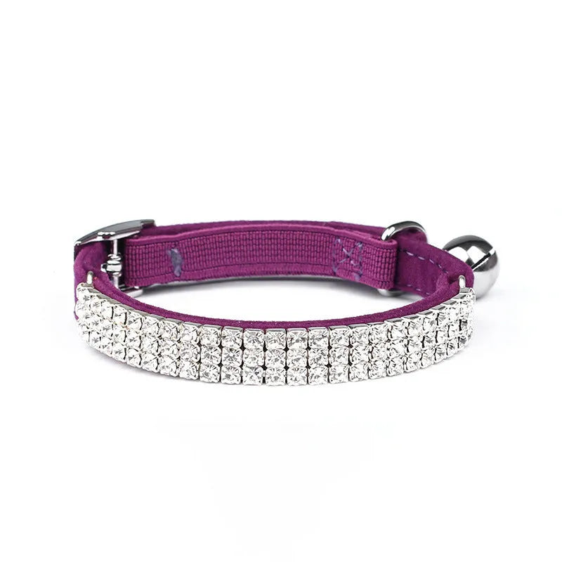 A soft red velvet cat collar with a line of rhinestones, showing the adjustable buckle.