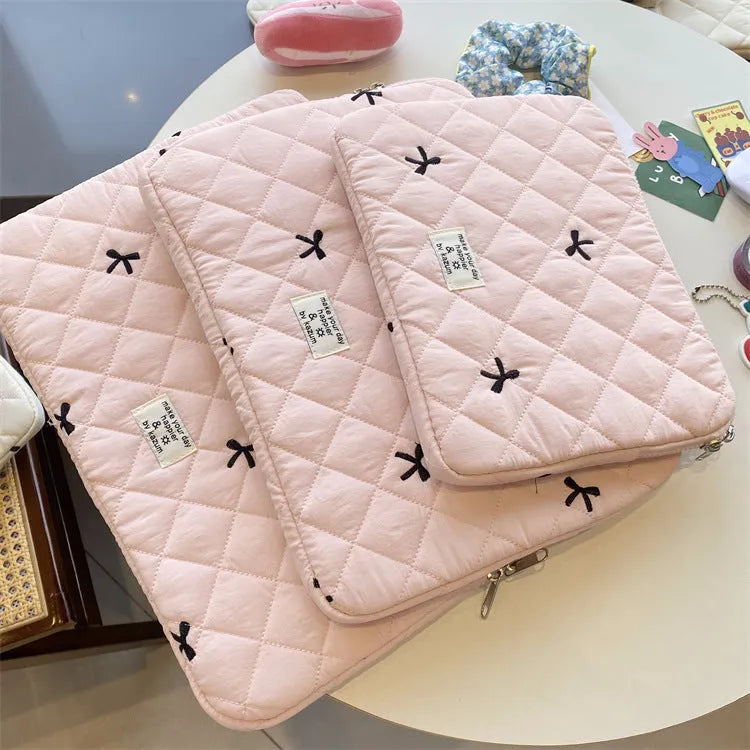 White nylon laptop bag with embroidered rhombus pattern and fabric bow, shown alongside black, light blue, and light pink colour options.