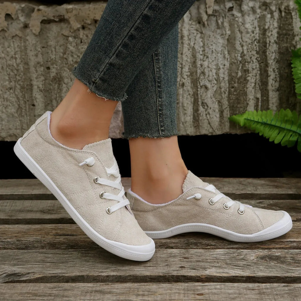 Creamy white low-top women's casual sneakers with a fabric upper and rubber sole.