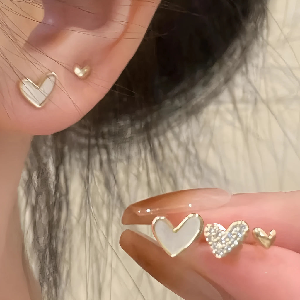 Three pairs of heart-shaped alloy earrings with electroplated finish in gold, black, and pink colours