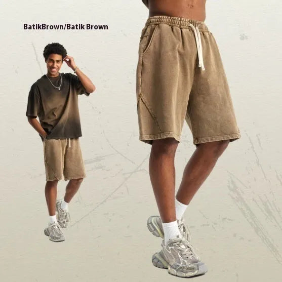 Man wearing batik-washed brown loose-fit cotton terry shorts on a casual street.
