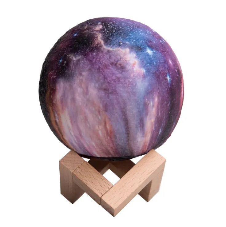 3D printed spherical lunar surface night light glowing with soft yellow and white LED light on a table.