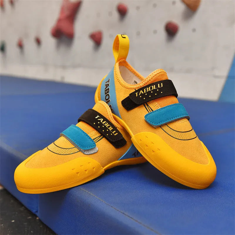 Black and red beginner rock climbing shoes with velcro strap and rubber sole on a climbing hold.