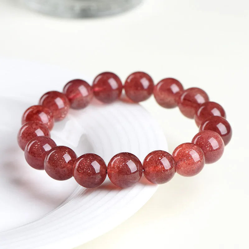 Natural cherry red strawberry quartz bracelet with geometry-shaped beads on a wrist.
