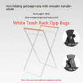 Black folding outdoor trash rack with wooden handle standing on a patio.