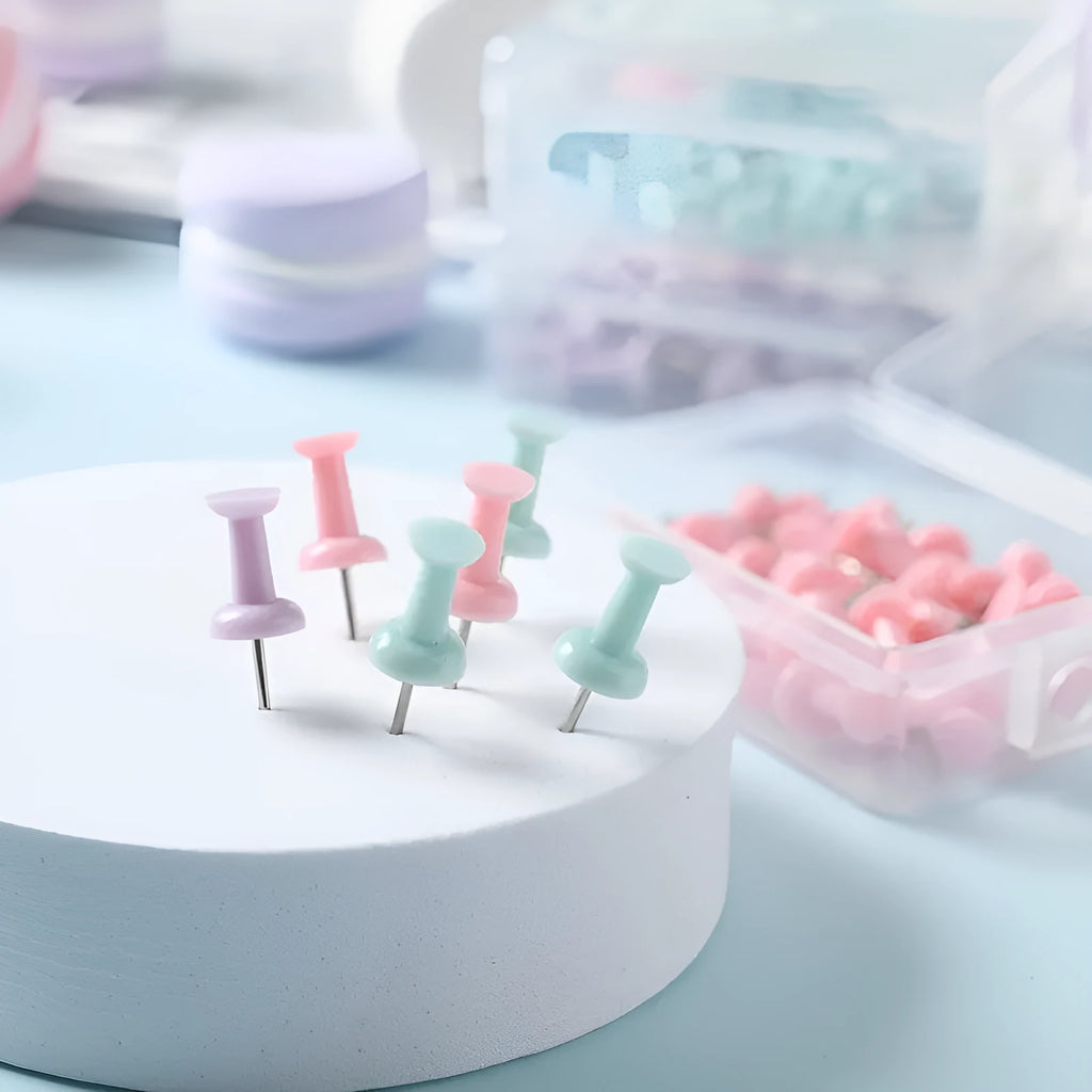 Plastic push pins in cherry blossom pink, mint green, and lavender, showing large and small sizes on a corkboard